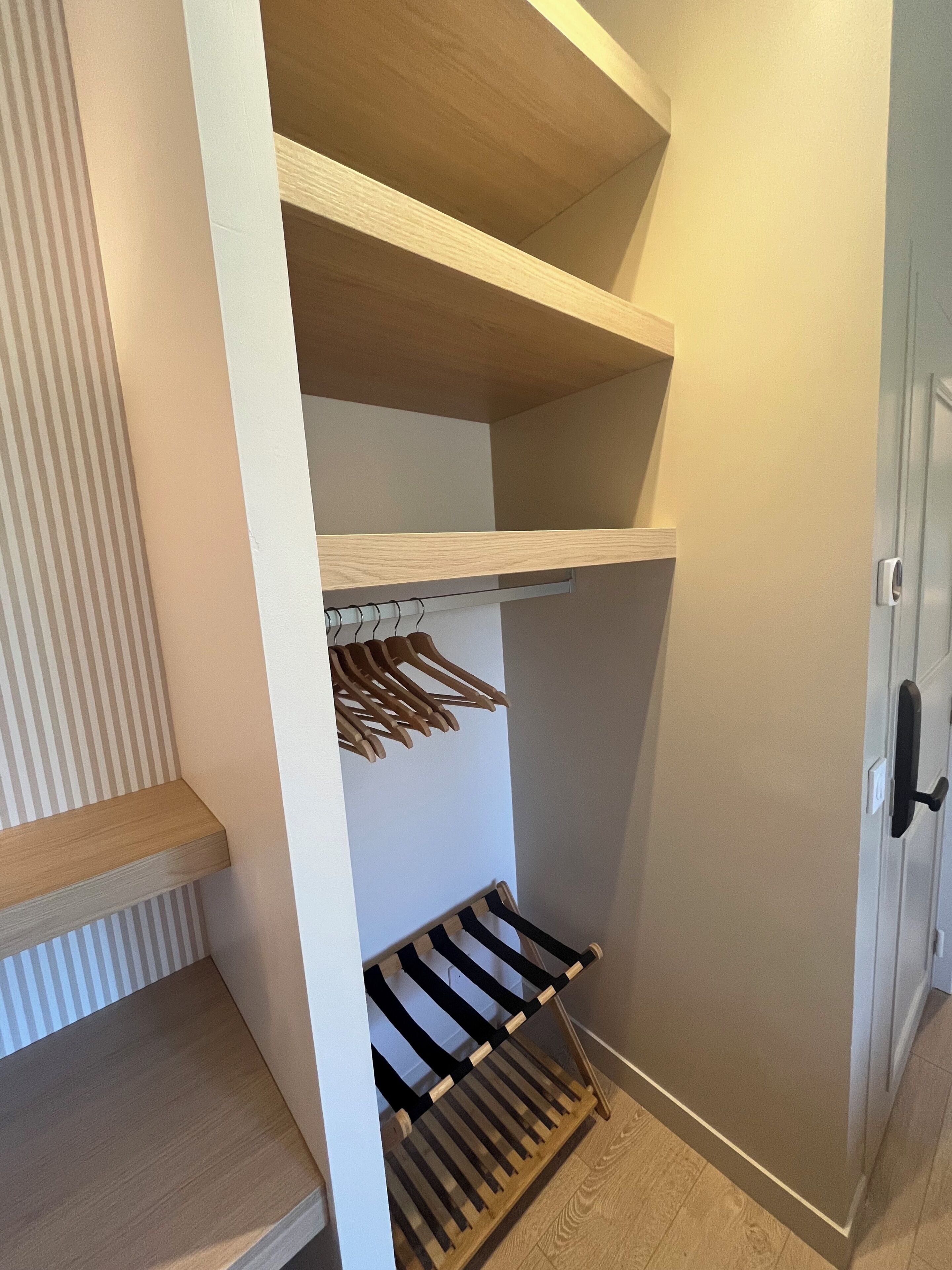 A closet with wooden shelves, a hanging rack, and a shoe rack.