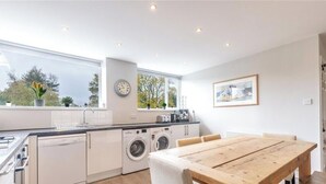 Una cocina moderna con comedor, ventanas grandes y un reloj en la pared.