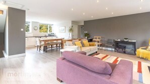 Een ruime woonkamer met een bank, een eettafel en een keuken op de achtergrond.