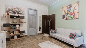 A living room with a sofa, a bookshelf, a door, and a painting on the wall. - Montereale Holiday House Apartment with Wi-Fi, Air Conditioning and Sauna on Request (Monreale)