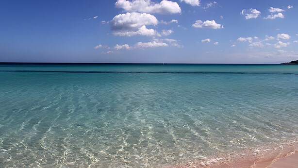 A clear turquoise sea, a sandy beach, and a distant sailboat. - Montereale Holiday House Apartment with Wi-Fi, Air Conditioning and Sauna on Request (Monreale)
