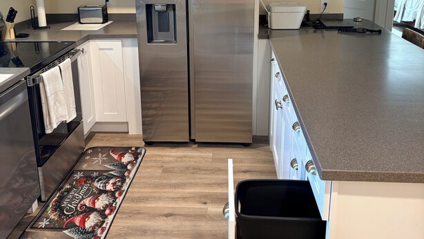 Una cocina moderna con armarios blancos, electrodomésticos de acero inoxidable y suelo de madera.
