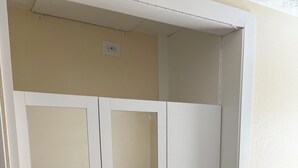 Un armario blanco con dos puertas espejadas y un estante inferior.