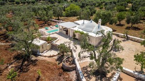 An aerial view of a villa with a swimming pool, stone walls, and surrounding olive trees. - Trullo Cecapesce by Perle di Puglia (Carovigno)