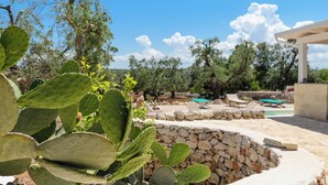 A stone wall, outdoor seating, and a pool area. - Trullo Cecapesce by Perle di Puglia (Carovigno)