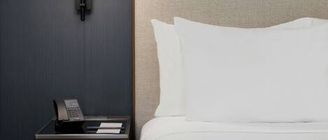 A hotel room with a bed, a nightstand, a lamp, and a telephone.
