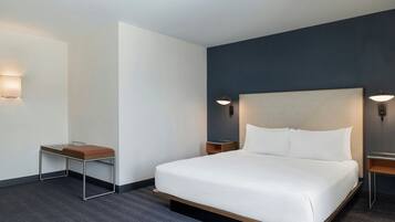 A hotel room with a single bed, a small table, two bedside tables, and wall-mounted lamps.