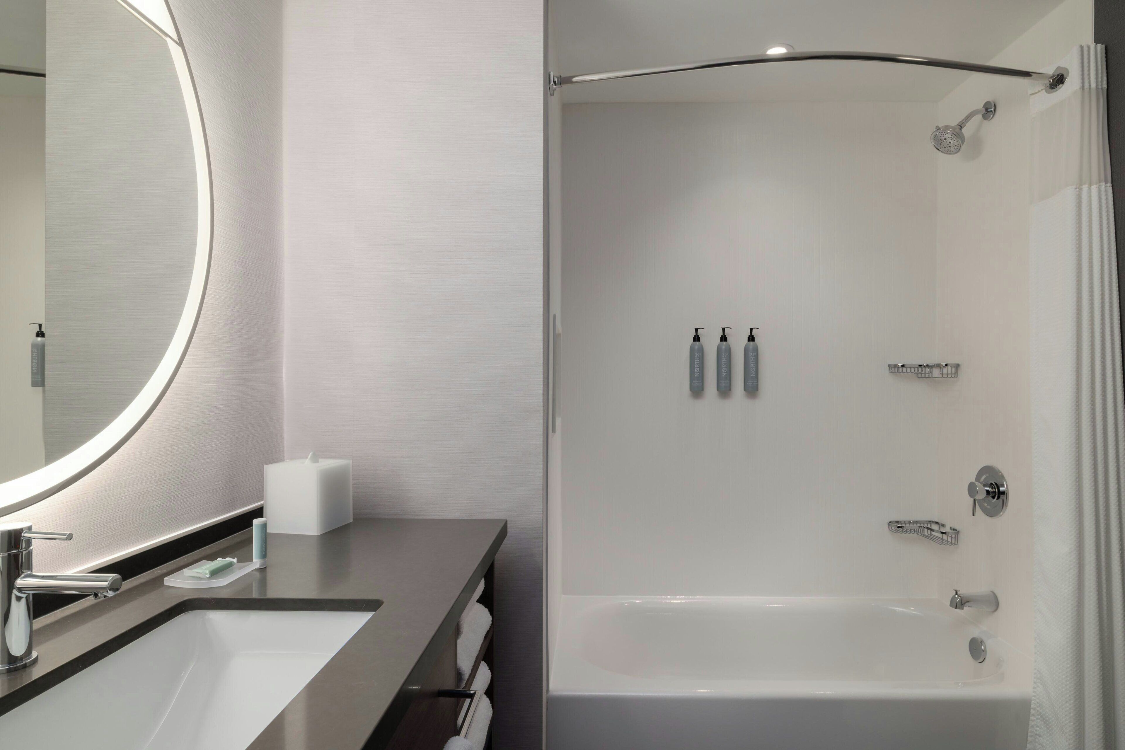 A modern bathroom with a sink, mirror, and shower.