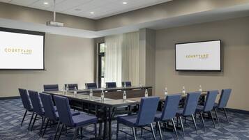 A conference room with a long table, blue chairs, and two screens displaying 'COURTYARD BY MARIEOTTA'.