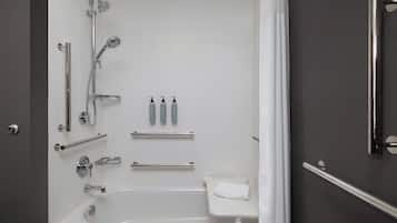 Un baño moderno con bañera, ducha, barras de apoyo y un inodoro.