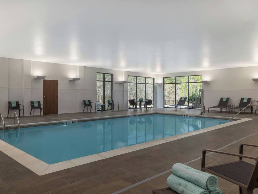 An indoor swimming pool with clear water, surrounded by lounge chairs and a door.