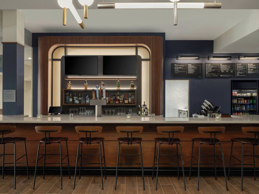 A bar area with a counter, stools, and a menu board.