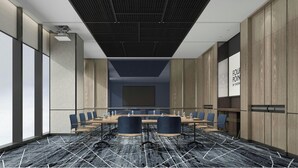 Une salle de conférence avec une longue table, des chaises et un grand écran.