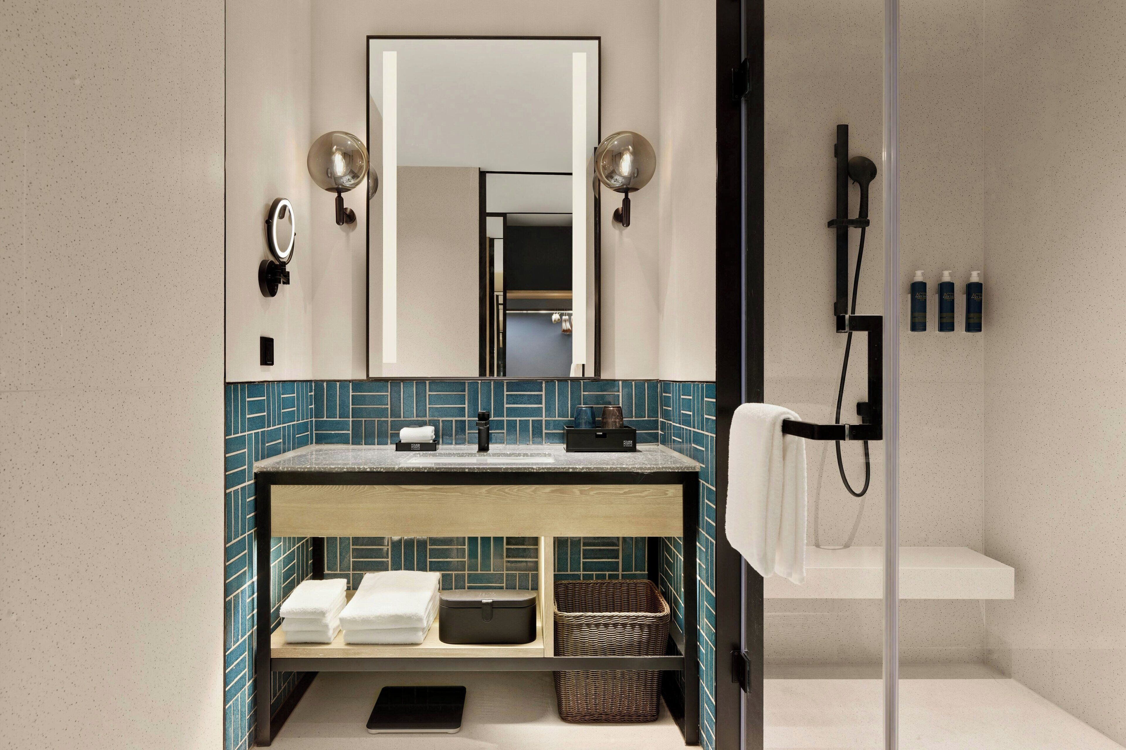 Un baño moderno con tocador de madera, un espejo grande y cabina de ducha de vidrio.