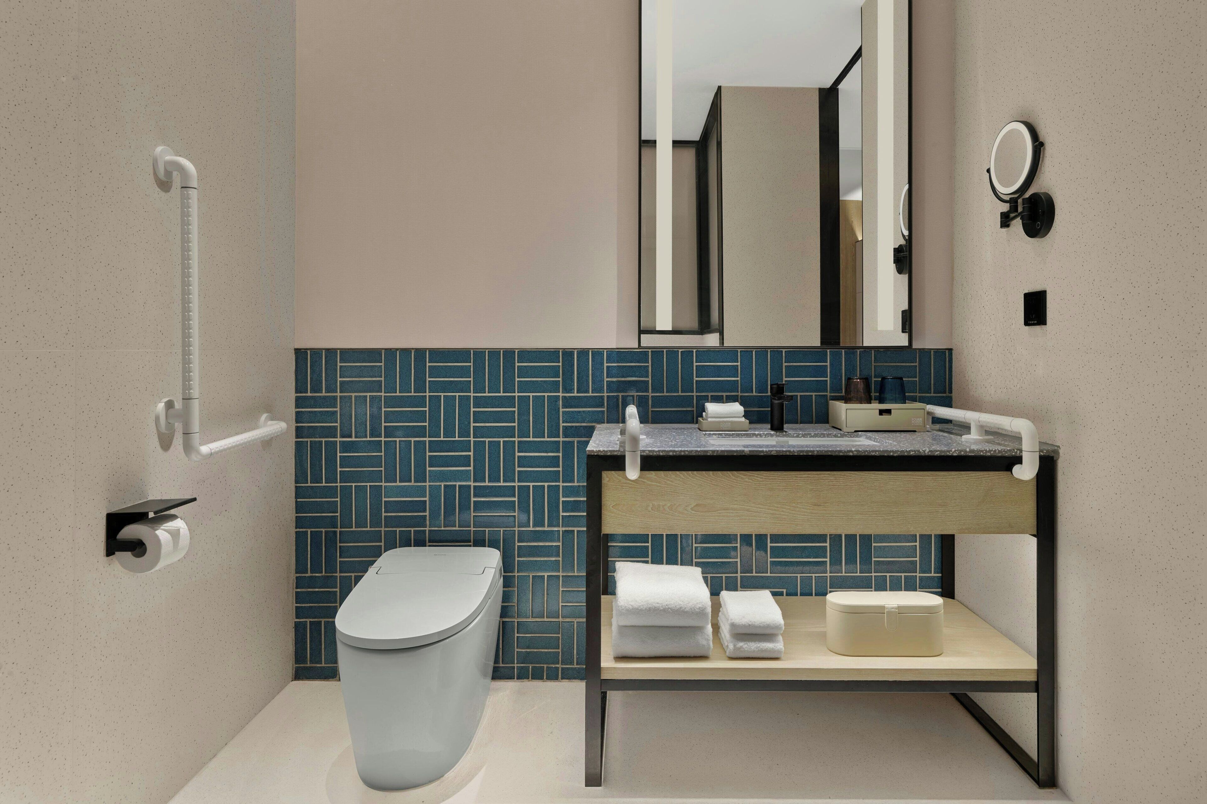 A modern bathroom with a toilet, sink, and mirror.