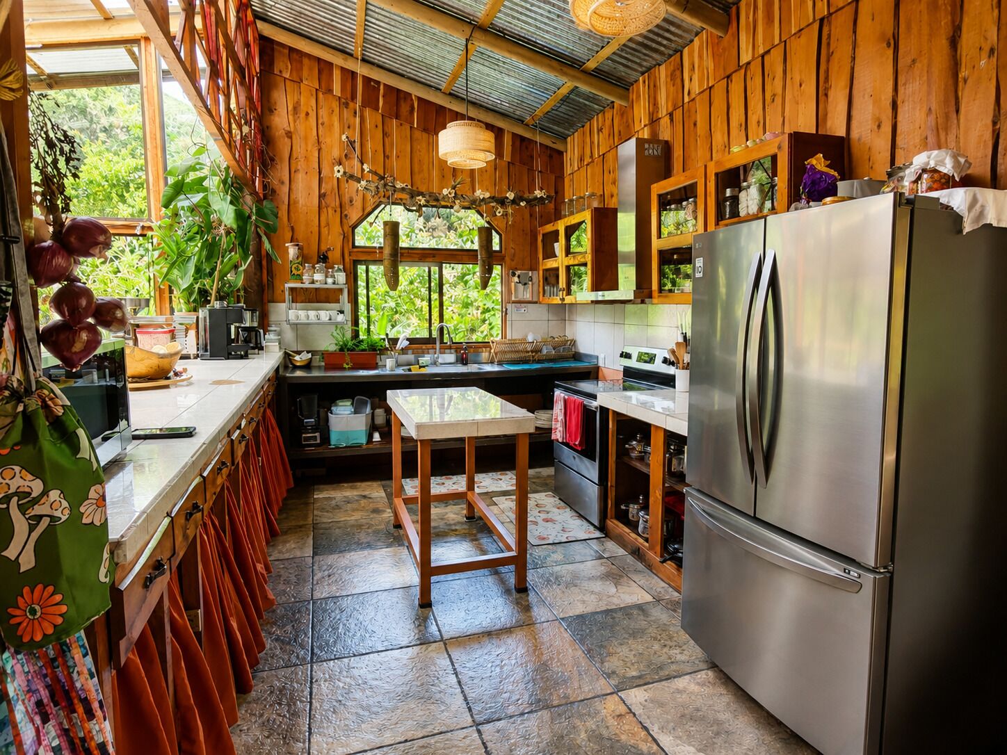 Una cucina con mobili in legno, un frigorifero in acciaio inossidabile e una finestra vista verde.