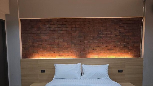 A modern bedroom with a brick-patterned headboard, a wooden bed frame, and a white bedspread. - SSP Residence Bang Bua Thong (Bang Bua Thong)