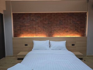 A modern bedroom with a brick-patterned headboard, a wooden bed frame, and a white bedspread. - SSP Residence Bang Bua Thong (Bang Bua Thong)