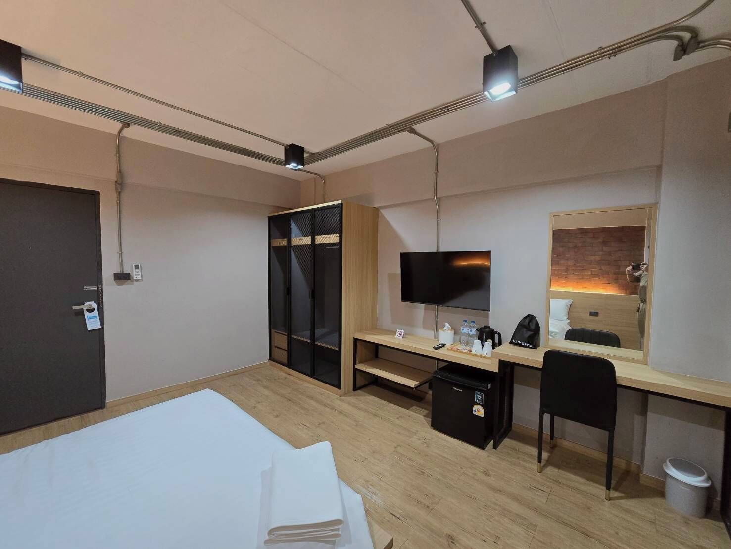 A hotel room with a bed, desk, chair, TV, and a mirror.