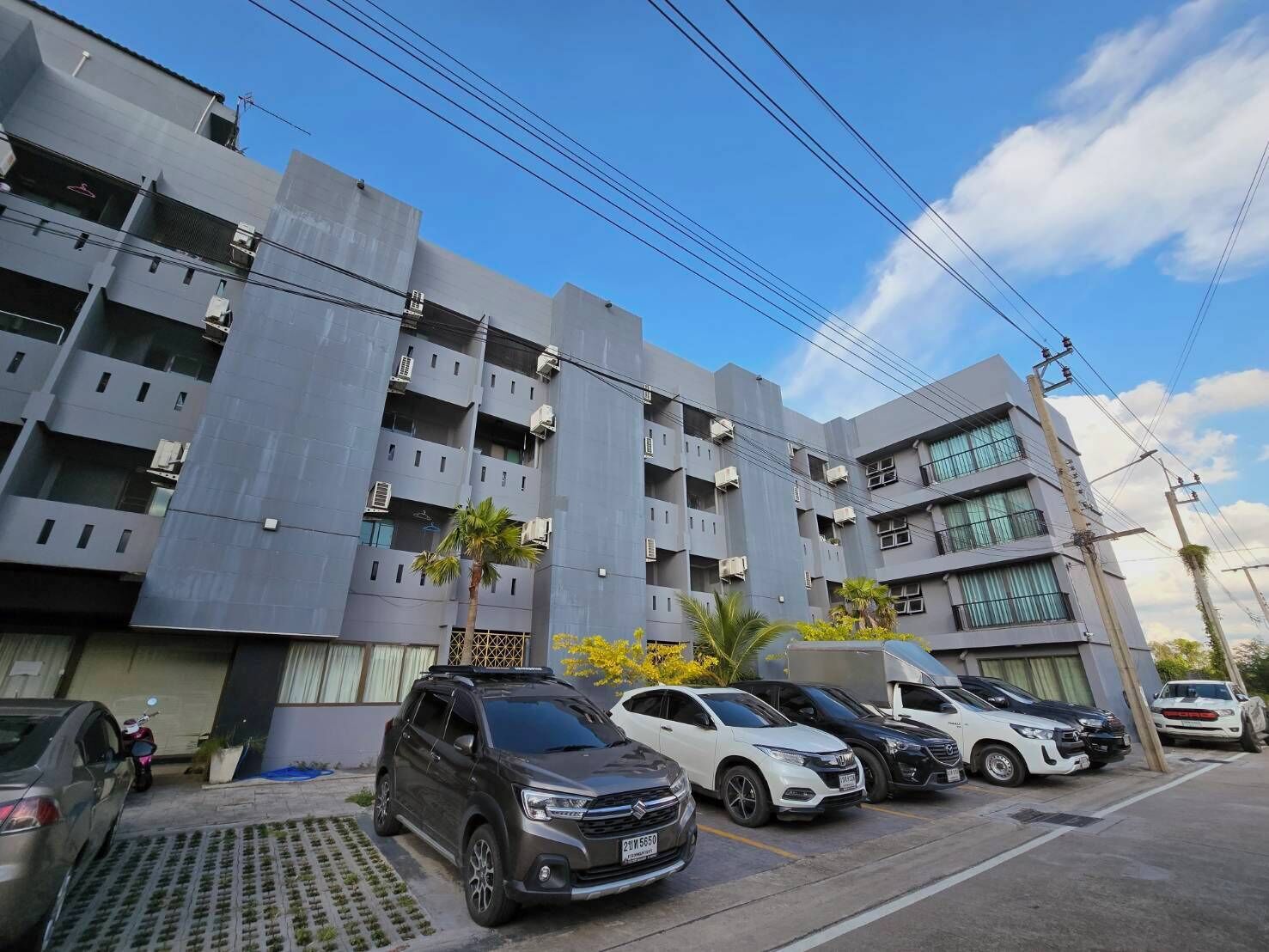 A modern multi-story building with a parking lot in front.