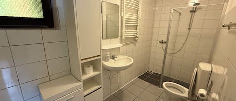 Een douche, handdoeken, zeep, toiletpapier