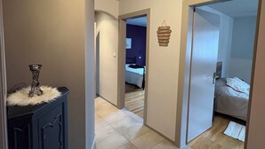 Un pasillo con un mueble oscuro de madera, un tapete blanco y mullido, y un cartel colgante con texto.