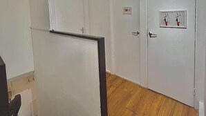 Eine Treppe führt zu einem Raum mit weißen Wänden und Holzboden. Eine Tür ist mit einem kleinen Bilderrahmen und einem Schild darüber versehen.