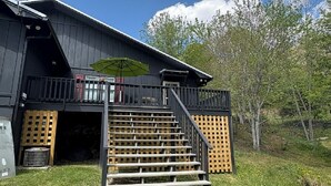 En byggnad med en balkong, utomhusplatser och en trappa som leder till en överbyggd entré.