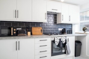 Eine moderne Küche mit weißen Schränken, einer schwarzen Mikrowelle, einem Toaster und einer Holztischplatte.