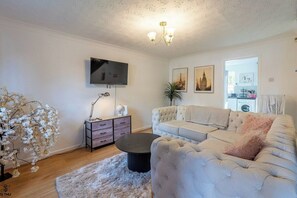 A living room with a sofa, a coffee table, a TV, and a plant. - M13 Manchester 2 Bed | Parking | 15% Discount (Manchester)