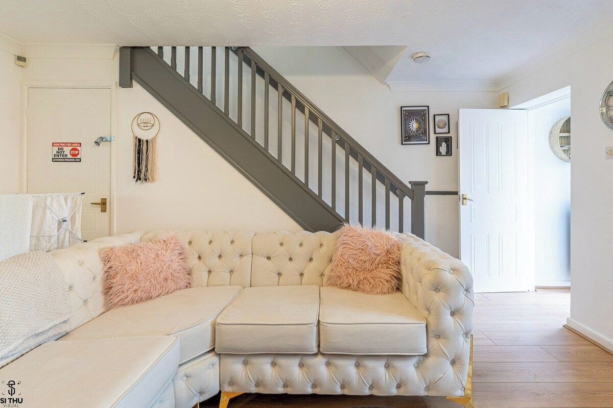 A living room with a sectional sofa, a staircase, and a door with a sign.