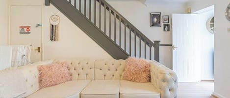 A living room with a sectional sofa, a staircase, and a door with a sign.
