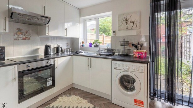 A kitchen with a built-in oven, a washing machine, and a window with a view of the outside. - M13 Manchester 2 Bed | Parking | 15% Discount (Manchester)