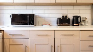 A kitchen with a microwave, toaster, and coffee maker on the counter. - Modern 3BR Home | Parking | Heart of West Didsbury (Manchester)