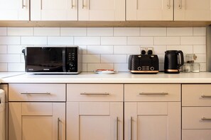 A kitchen with a microwave, toaster, and coffee maker on the counter. - Modern 3BR Home | Parking | Heart of West Didsbury (Manchester)