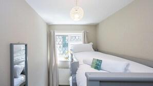 A hotel room with a bunk bed, a bedside table, a mirror, and a window with curtains. - Modern 3BR Home | Parking | Heart of West Didsbury (Manchester)