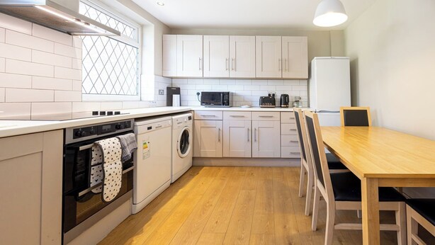 A modern kitchen with a built-in oven, microwave, and washing machine. - Modern 3BR Home | Parking | Heart of West Didsbury (Manchester)