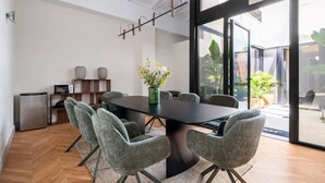 Une salle de réunion moderne, dotée d’une grande table, de chaises grises à revêtement en tissu, d’une plante en pot et offrant une vue sur l’espace extérieur grâce à des portes vitrées.
