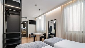 Una habitación de hotel moderna con dos camas, un escritorio y un espejo.