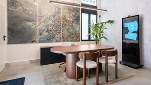 Une salle de conférence moderne avec un grand mur de marbre, une table ronde et quatre chaises.