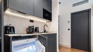 Une cuisine compacte équipée d’un four à micro-ondes, d’une machine à café et d’un réfrigérateur.