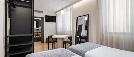 Una habitación de hotel moderna con dos camas, un escritorio y un espejo.