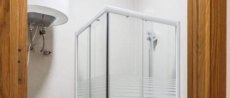 A modern bathroom with a glass-enclosed shower, a toilet, and a white sink.