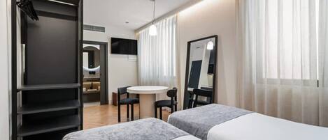 A modern hotel room with two beds, a desk, and a mirror.