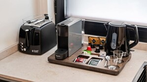 A kitchenette with a toaster, a coffee maker, and a tray with coffee pods, a kettle, and glasses. - Pacifico Accessible Suite Near Retiro (Madrid)