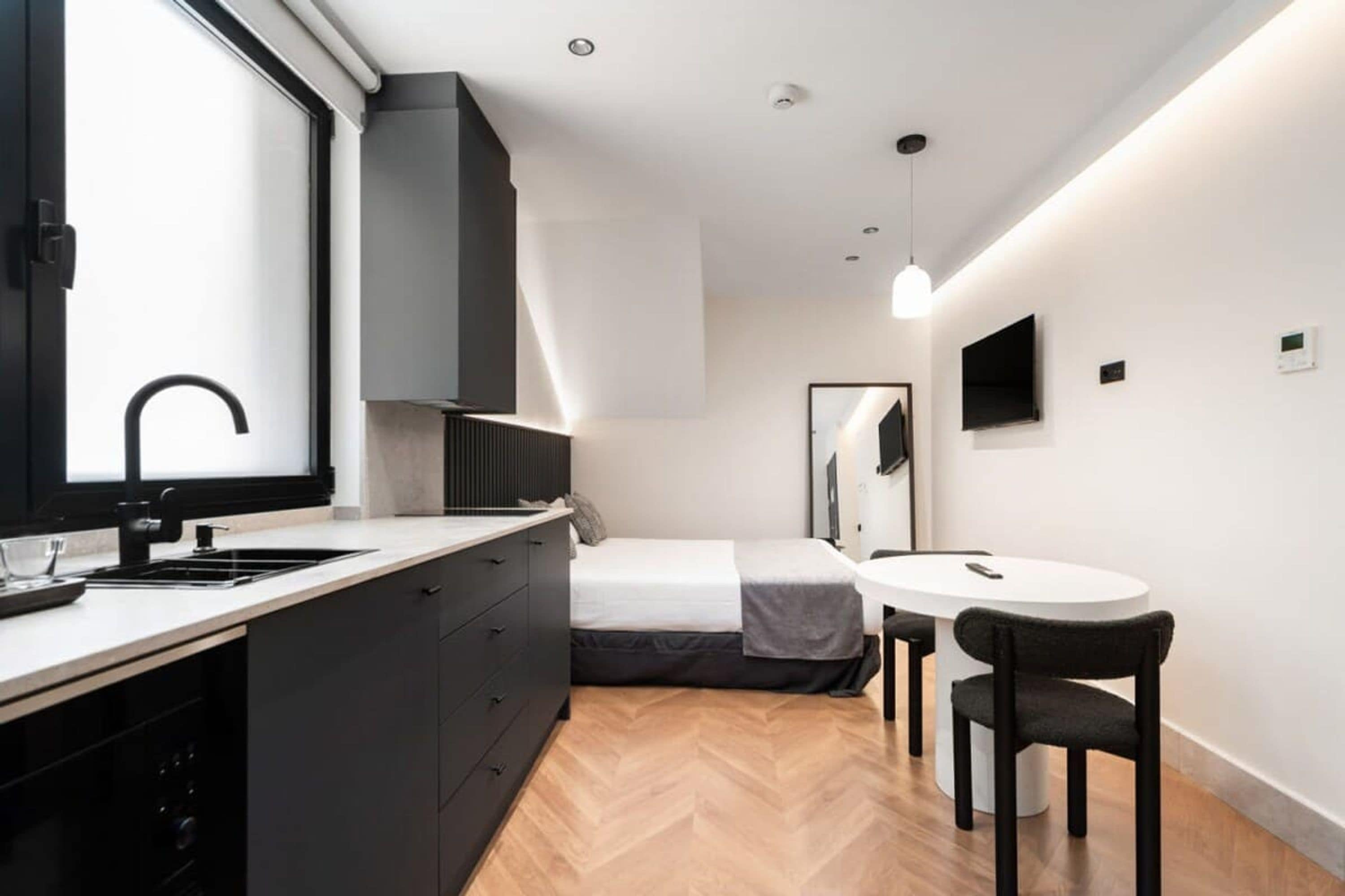 A compact bedroom with a bed, bedside table, and a small window.