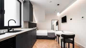 A compact bedroom with a bed, bedside table, and a small window.