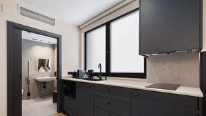 A modern kitchen with dark cabinetry, a countertop, and a window above the sink. - Pacifico Accessible Suite Near Retiro (Madrid)