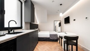 A compact bedroom with a bed, bedside table, and a small window. - Pacifico Accessible Suite Near Retiro (Madrid)