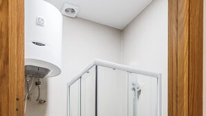 Un baño moderno con ducha de mampara de vidrio, inodoro y lavabo blanco.
